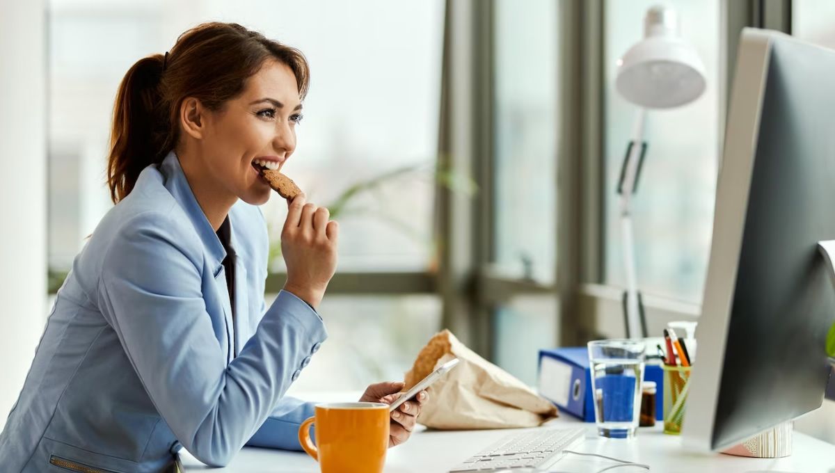 Mujer comiendo mientras trabaja (Fuente: Freepik)