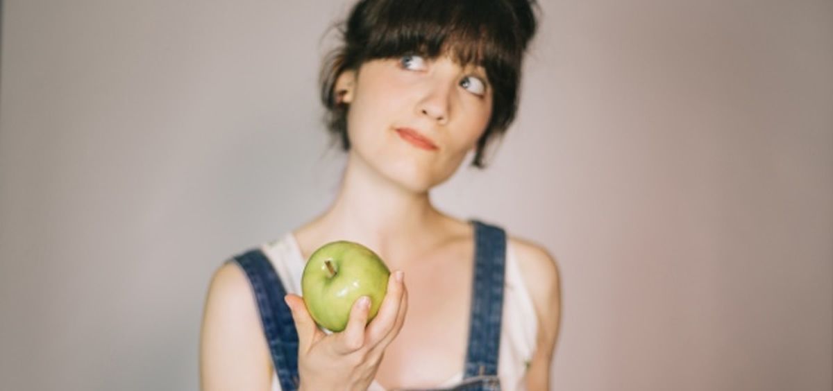 Mujer pensando en comerse una manzana (Foto. Freepik)