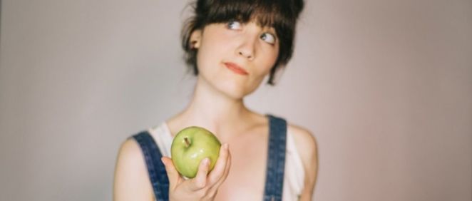 Mujer pensando en comerse una manzana (Foto. Freepik)