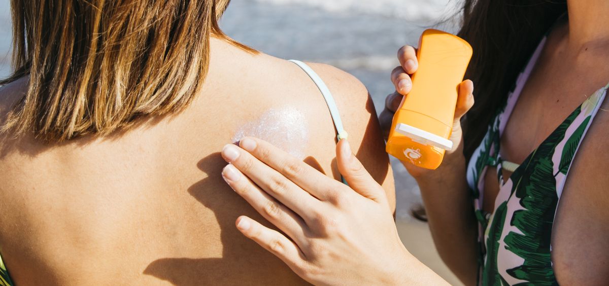 Una mujer le aplica crema solar sobre la espalda a otra (Foto. Freepik)
