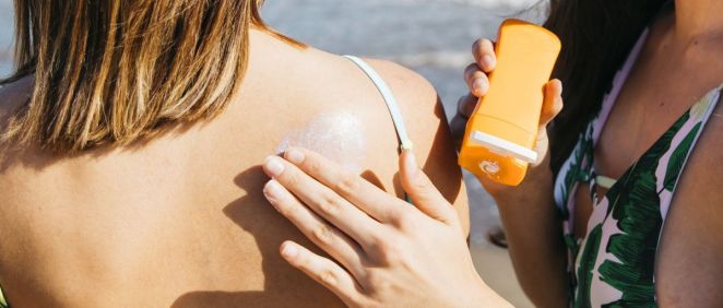 Una mujer le aplica crema solar sobre la espalda a otra (Foto. Freepik)