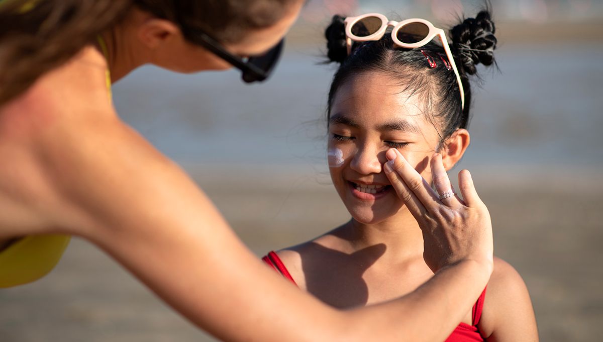 Madre aplicándole crema solar en la cara a su hija (Foto. Freepik)