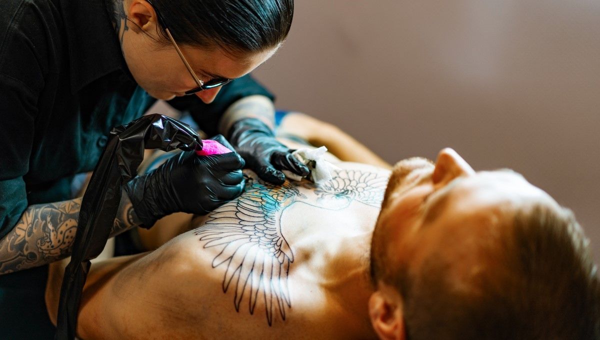 Tatuadora haciendo un tatuaje a un hombre en el pecho (Foto. Freepik)