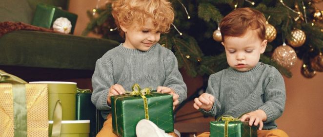 Dos niños abriendo regalos bajo el árbol de Navidad (Foto. Freepik)