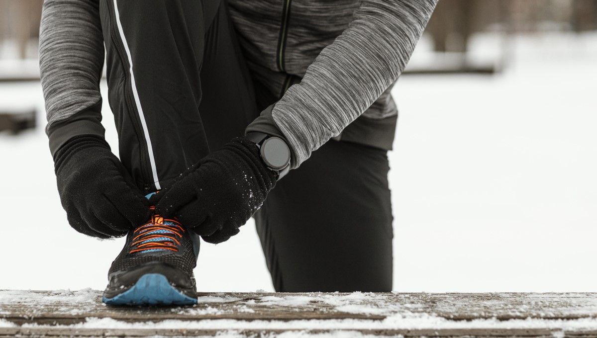 Persona atando sus cordones antes de correr entre la nieve (Foto. Freepik)
