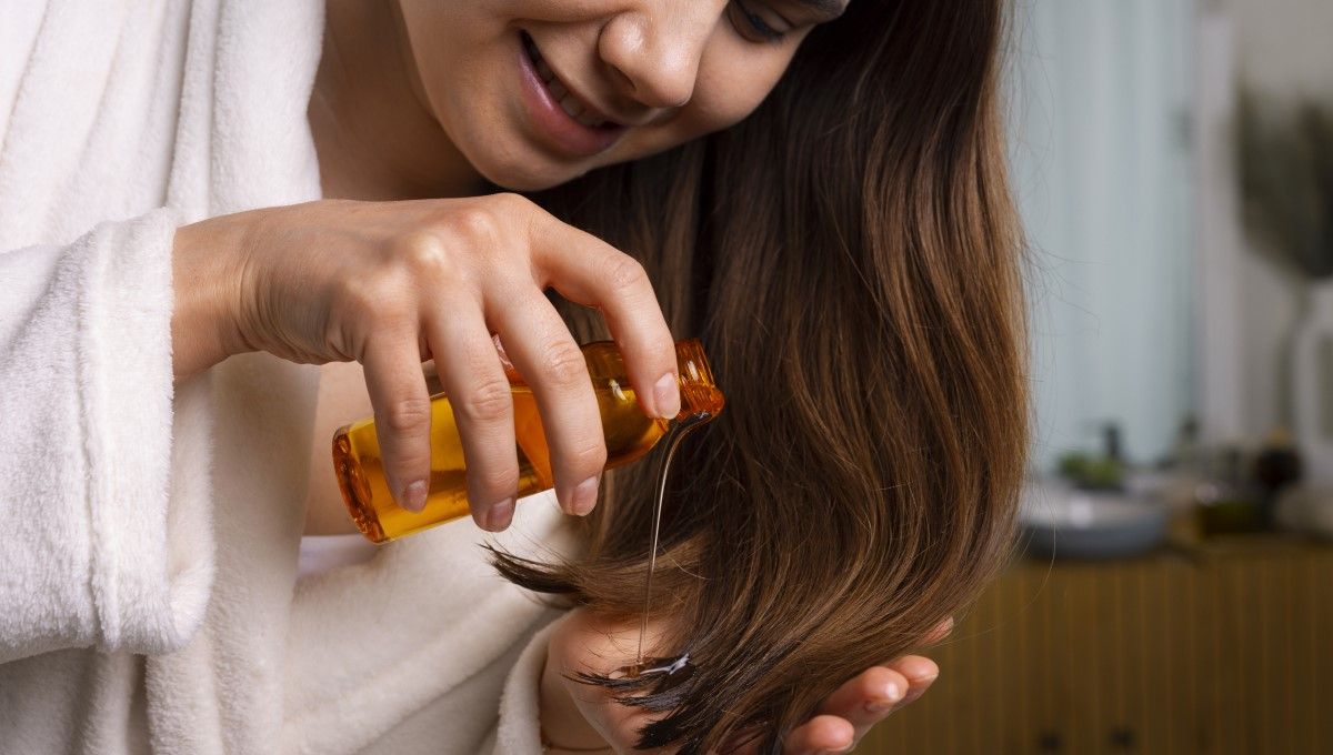 Mujer aplicando aceite en las puntas de su cabello (Foto. Freepik)