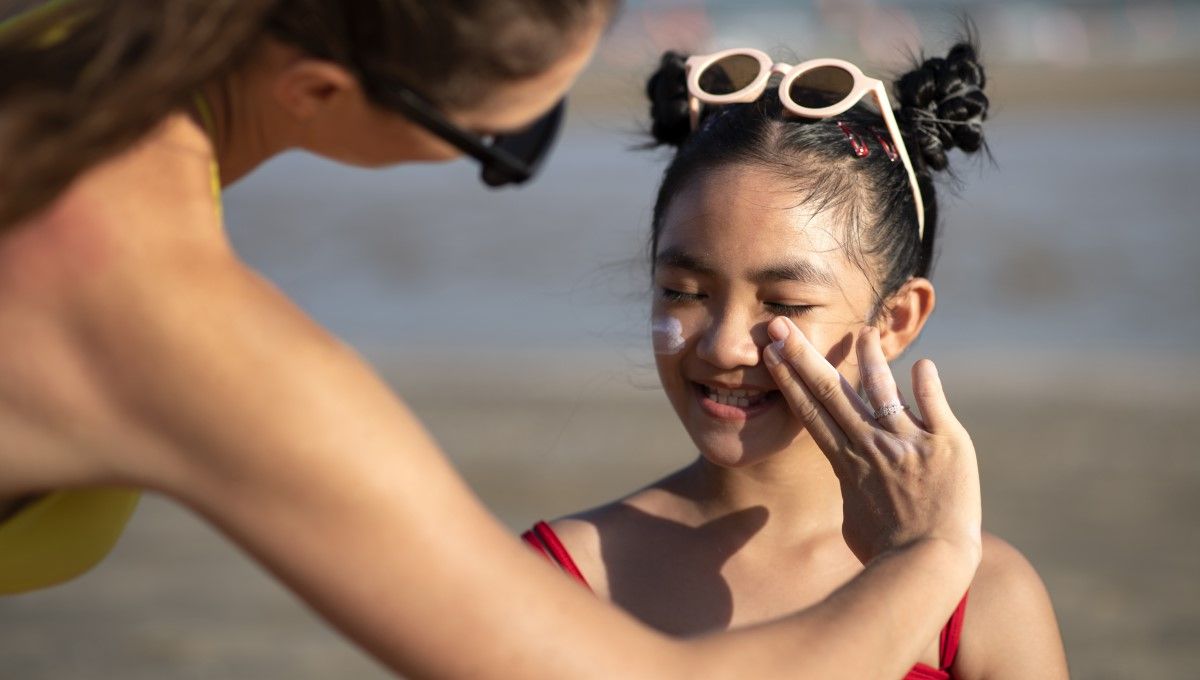 Una mujer le aplica protector solar a una niña en el rostro para proteger la piel de la radicación solar (Foto. Freepik)