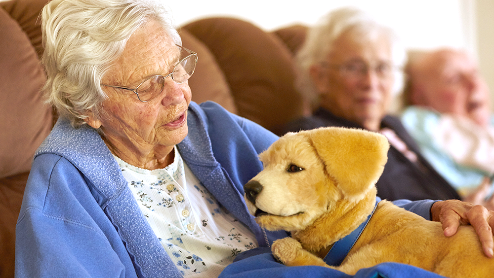 Anciana con demencia junto al perro robot (Foto: Tombot)