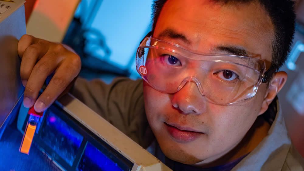 El estudiante graduado de la Universidad de Rice, Bo Jiang, muestra un vial fluorescente (Foto. Universidad de Rice)