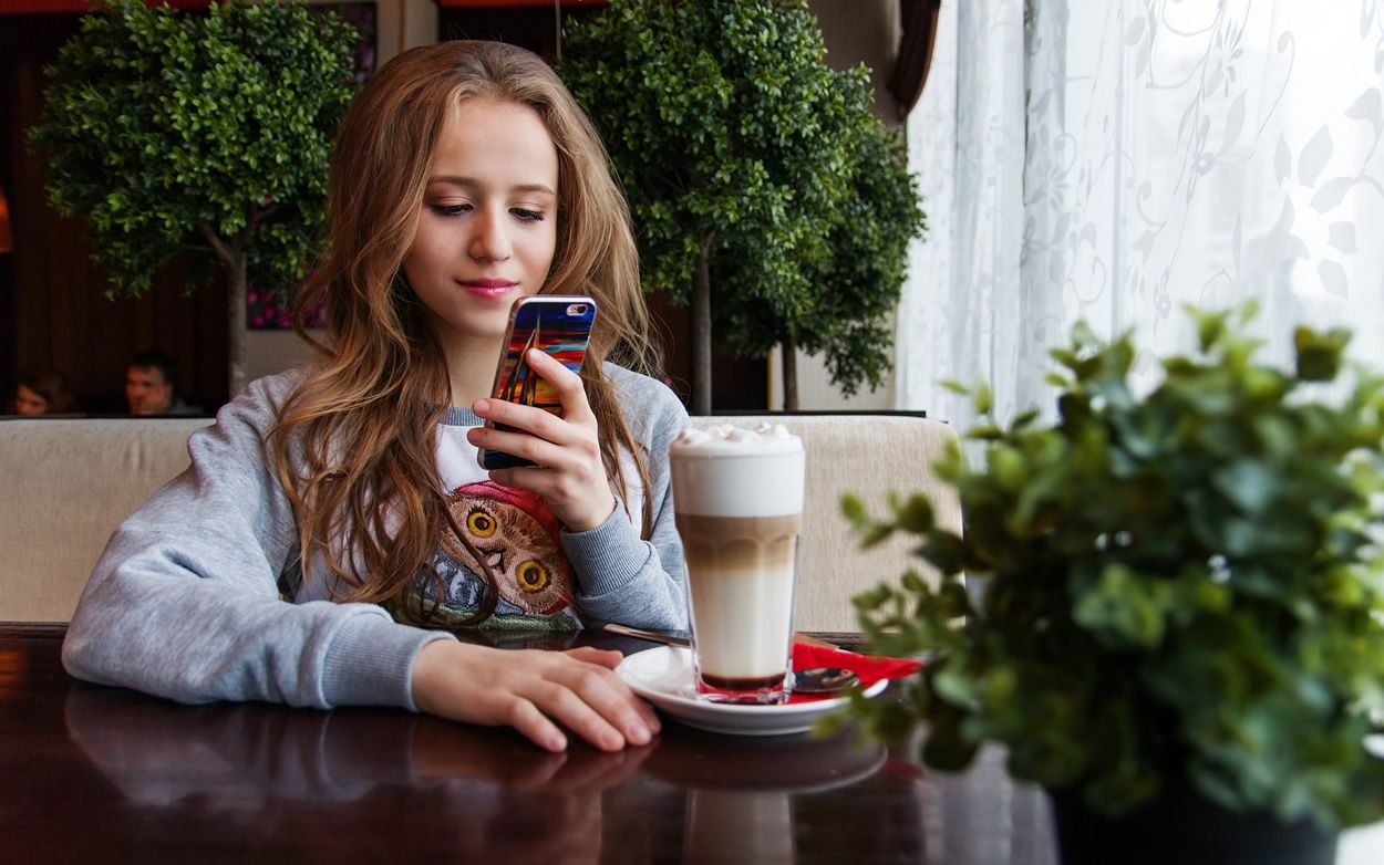 Una chica interactúa con su móvil en una cafetería