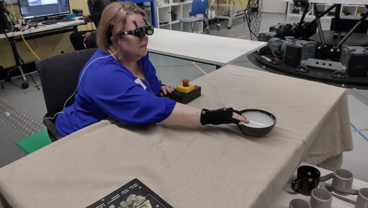 Un miembro ciego del equipo de investigación utiliza el tacto acústico para localizar y alcanzar un objeto sobre la mesa. (Foto: Lil Deverell)