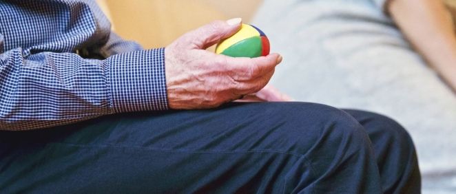 Un anciano realiza ejercicios de movilidad con una pequeña pelota
