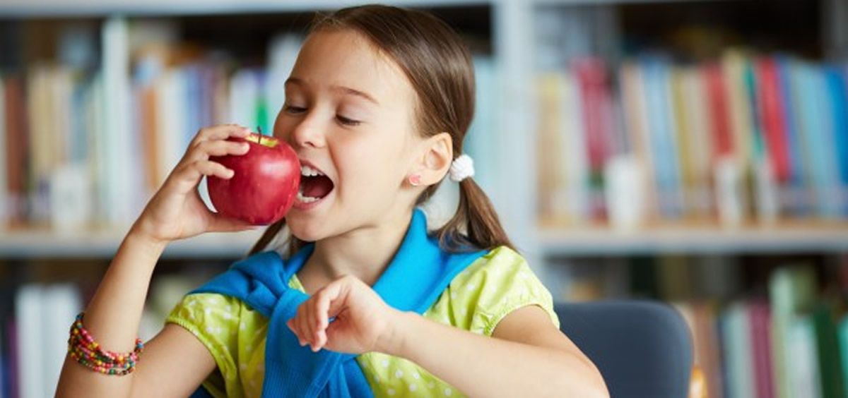 NIña comiendo manzana en la escuela (Foto. Freepik)