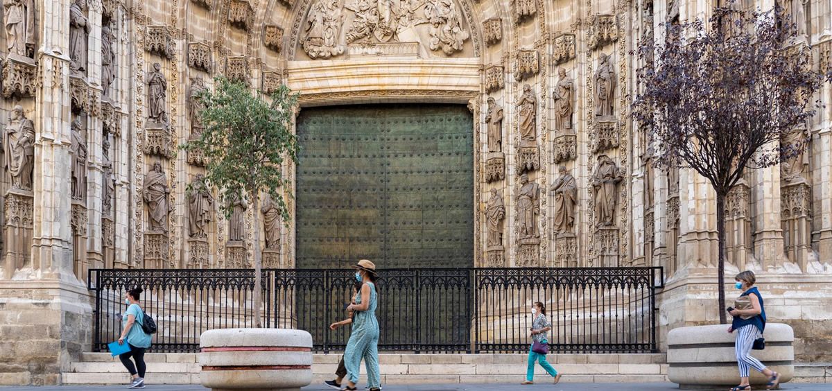 Paseantes por la puerta de la Anunciación de la Catedral de Sevilla en el primer día de uso obligatorio de mascarillas en Sevilla. (Foto. Eduardo Briones Europa Press)