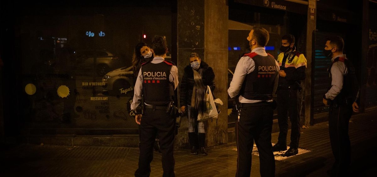 Varios Mossos d'Esquadra paran a una persona durante un control por el toque de queda impuesto a raíz de la crisis sanitaria del Covid 19 (Foto. David Zorrakino   Europa Press)