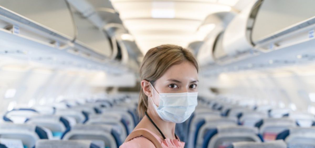 Mujer con mascarilla en el interior de un avión (Foto: Freepik)