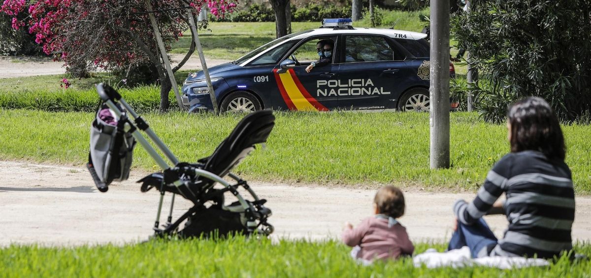 Una madre sentada en el césped junto a su hija ven pasar un coche de la Policía Nacional (Foto. Rober Solsona   Europa Press )