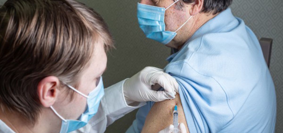 Profesional sanitario administrando una vacuna a un anciano