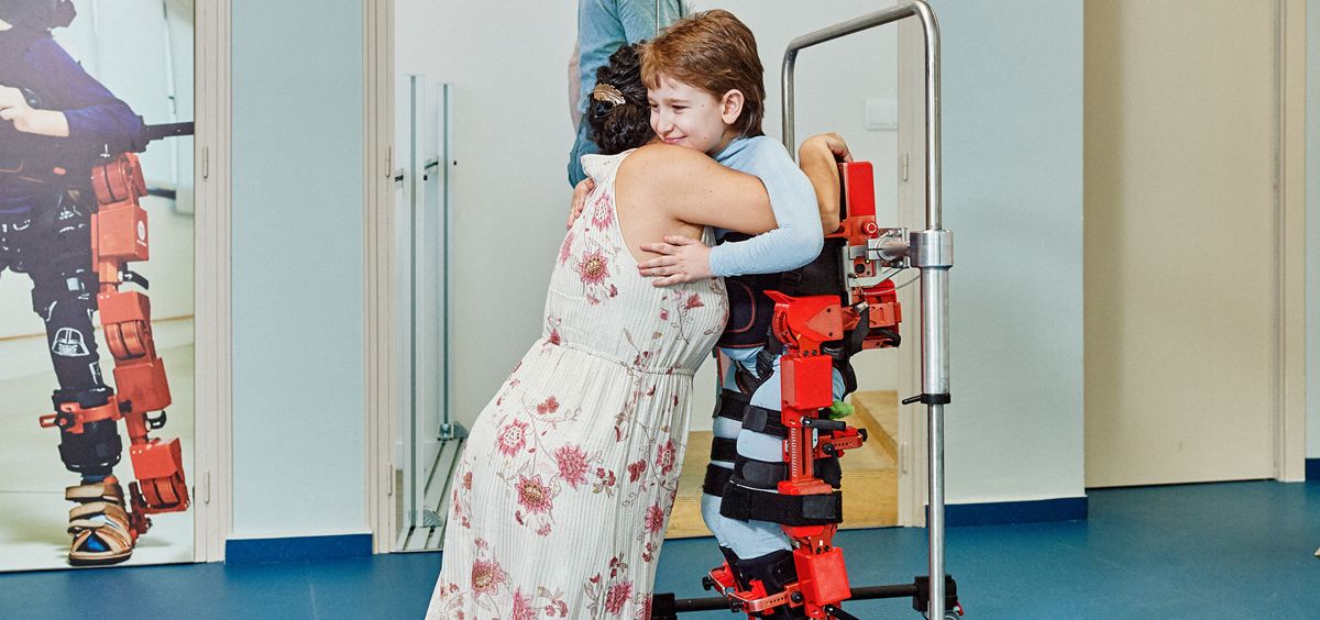Un niño con AME en su terapia con exoesqueleto abraza a su madre (Foto. Marsi Bionics)