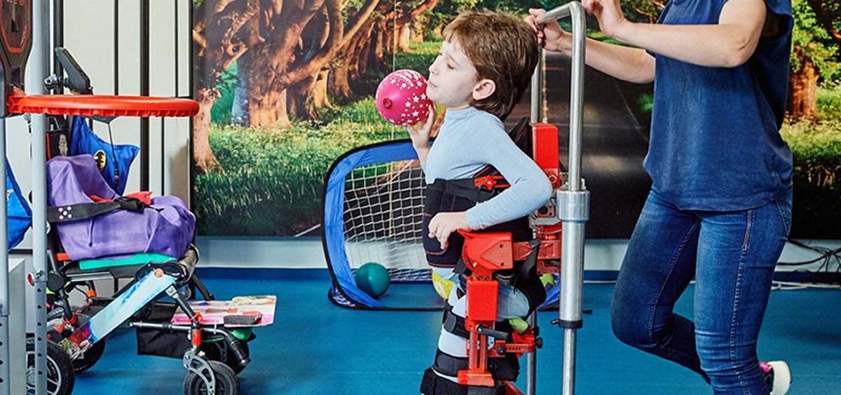 Un niño con AME lanza una pelota en terapia con el exoesqueleto (Foto. Marsi Bionics)