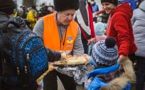 Un voluntario ofrece pan caliente a un niño en Isaccea, Rumanía, que cruzó el Danubio con su madre en un ferry desde Ucrania (Foto. UNICEF/UN0602237/Câtu)