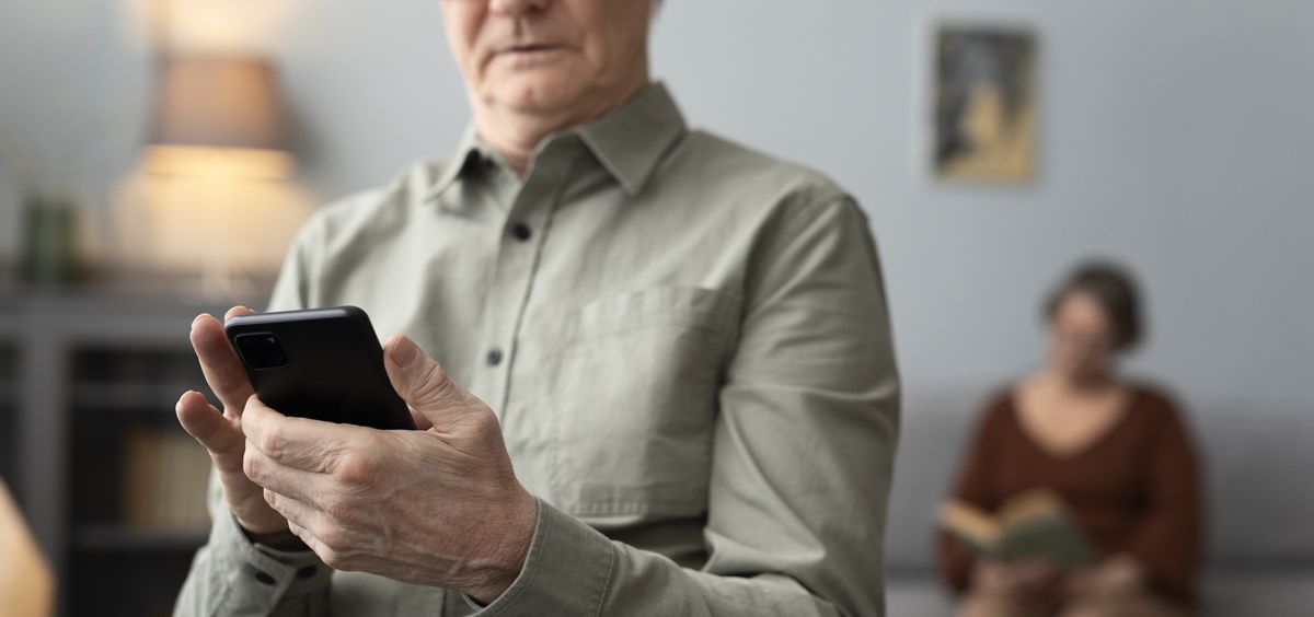 Una persona mayor usando un teléfono móvil en su casa (Foto: Freepik)
