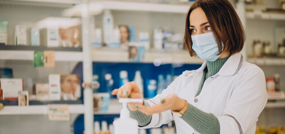 Una mujer farmacéutica usando mascarilla y gel de manos en una oficina de farmacia (Foto: Freepik)