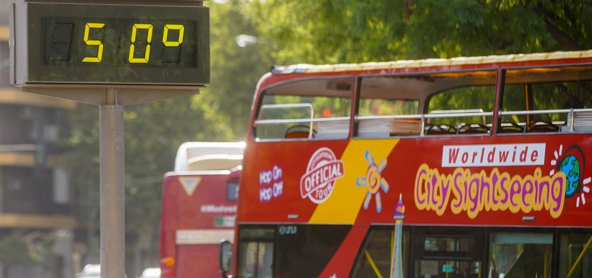 Un autobús turístico pasa sin pasajeros delante de un termómetro que marca 50º en Sevilla. (Foto. Eduardo Briones EP)