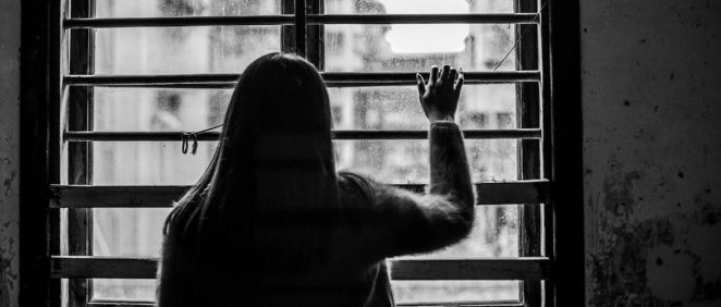Mujer mirando por ventana (Foto: Freepik)