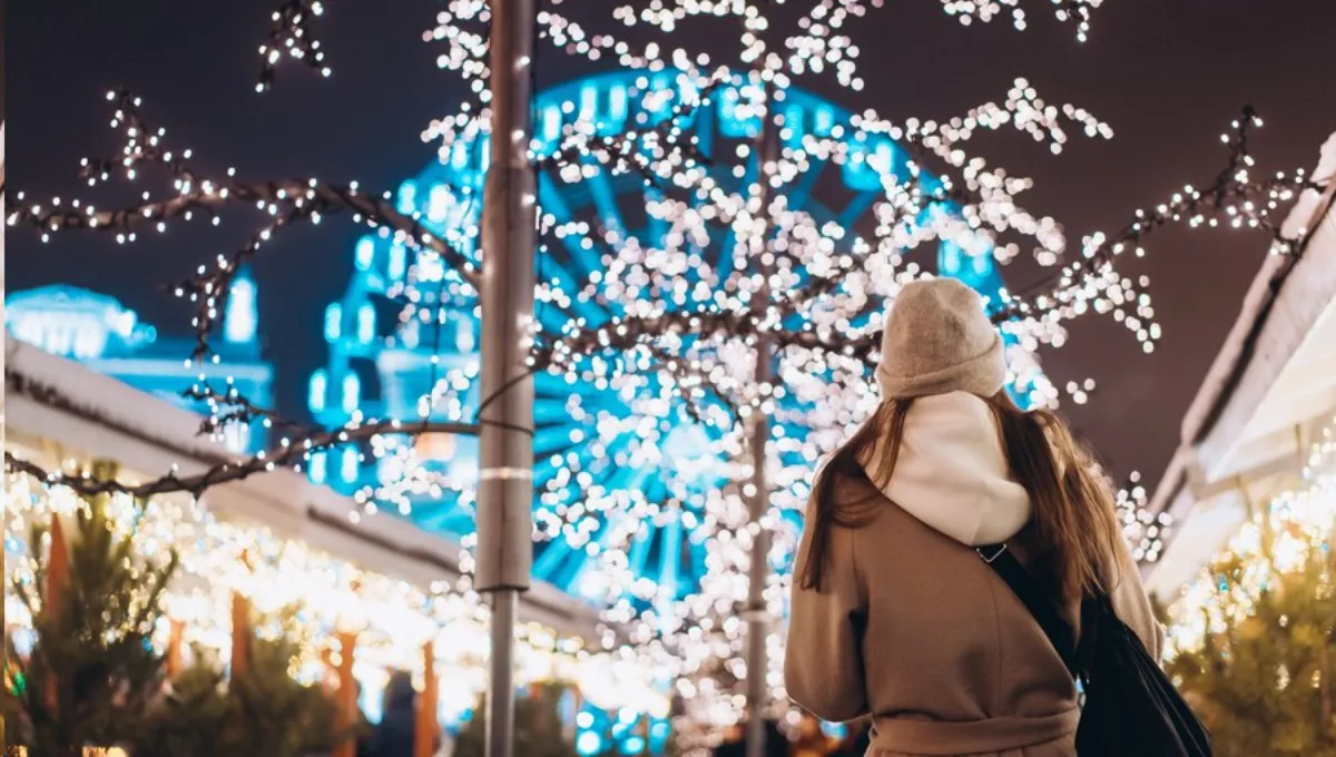 Mujer pasea frente a las luces navideñas. (Freepik)