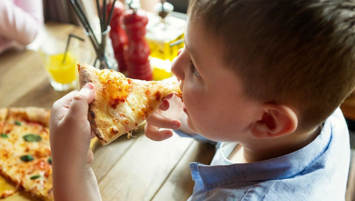 Niño en situación de vulnerabilidad económica comiendo pizza. (Foto: Freepik)