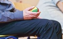 Un anciano realiza ejercicios de movilidad con una pequeña pelota